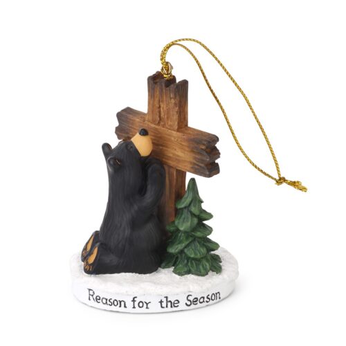 A black cat figurine praying by a wooden cross and Christmas tree.