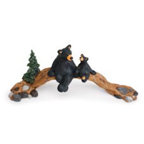 A decorative figurine of two black bears on a log with a tree.