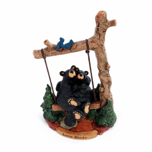 A small bear figurine on a wooden swing.
