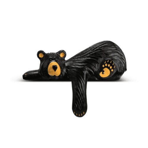 A black bear sculpture lying down with a paw extended.