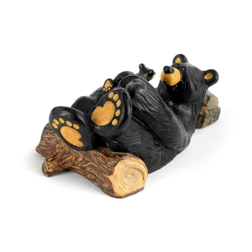 A black bear figurine lounging on a log with yellow paw pads.