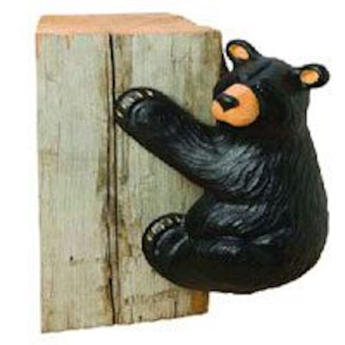 A decorative black bear climbing a wooden plank.