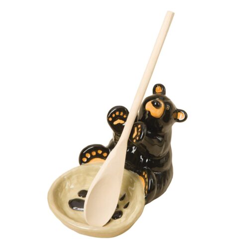 A ceramic bear-themed spoon rest with a wooden spoon.