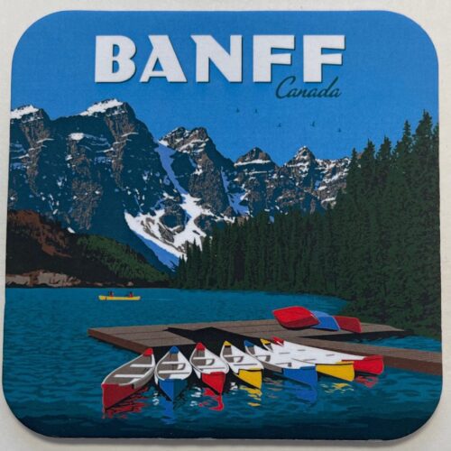 Colorful canoes lined up on a serene lake with mountains in the background at Banff.