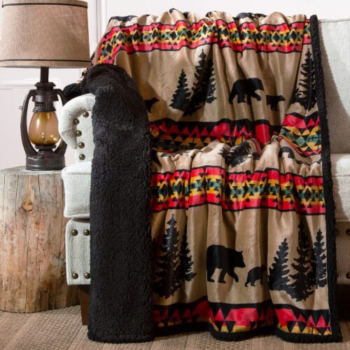 Cozy fleece blanket with bear and tree patterns draped over a chair.