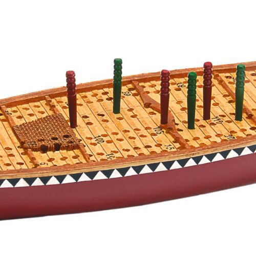 A wooden cribbage board with pegs on a red table.