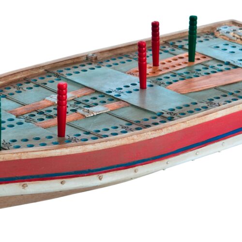 A wooden peg solitaire board shaped like a ship with red pegs.